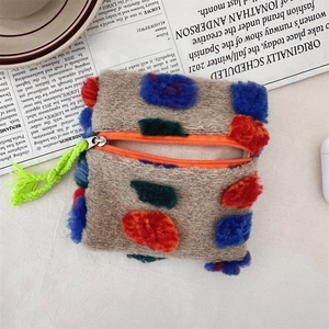 Close-up of gray plush makeup pouch with colorful dots and green woven rope zipper