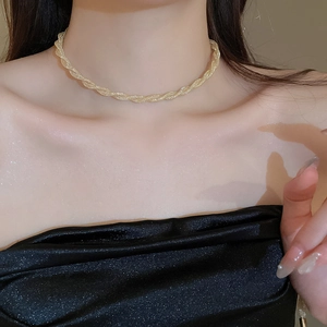 Close-up of gold twisted mesh necklace on model with sparkling skin for a luxury look