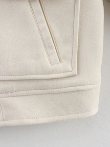 Détail de la poche cousue et du tissu en laine beige texturé sur la veste
