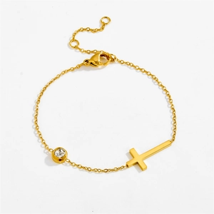 Elegant gold titanium cross bracelet with a round zircon stone on a white background