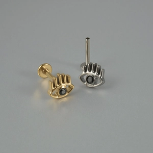 Gros plan de piercings labret or et argent avec motif œil et pierre précieuse noire