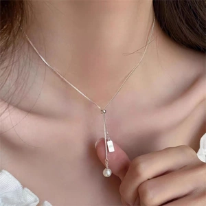 Close-up of pearl pendant necklace with silver chain on model collarbone