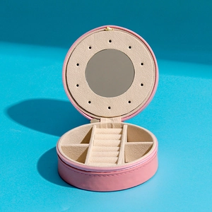 Detail view of pink PU leather round jewelry box featuring ear stud plate and vanity mirror
