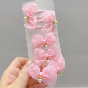 Detail of pink tulle bow hair clips featuring delicate pearl charms and gold accents