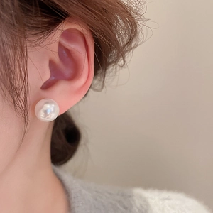 Close-up of elegant white pearl stud earring worn by model in a soft minimalist style