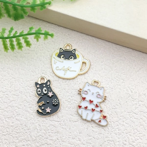 Macro shot of cartoon black and white cat enamel charms on a minimalist beige background