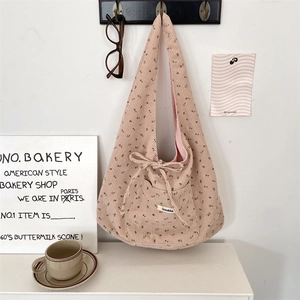 Close-up of pink corduroy shoulder bag with brown floral patterns and bow decoration