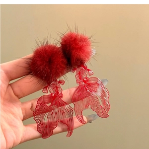 Detail of red hollowed-out goldfish earrings with plush pompoms and silver needles