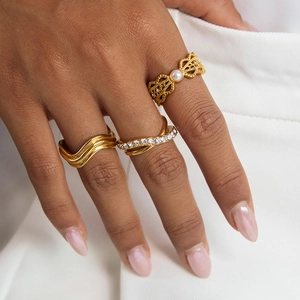 Detailed close-up of gold zircon rings featuring wavy patterns and vintage pearl accents