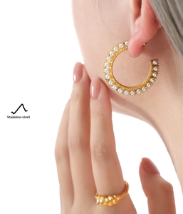 Detail of gold-plated stainless steel C-shape earrings with pearls on model