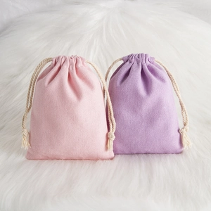 Pink and purple drawstring storage bags in cotton linen fabric on white plush surface
