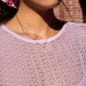 Close-up of layered stainless steel gold necklace with sparkling zircon pendants