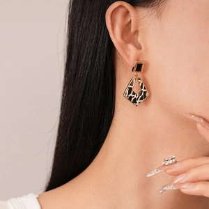Detail of vintage geometric earrings with black and white texture on model ear
