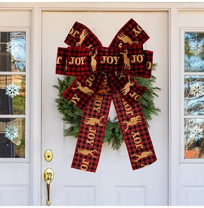 Detail of red and black buffalo plaid Christmas bow with golden JOY and reindeer print