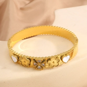Macro view of gold heart four-leaf flower bangle with shell inlay and star crystal