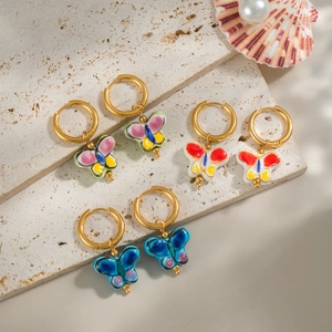 Three pairs of colorful butterfly hoop earrings on a beige travertine stone display