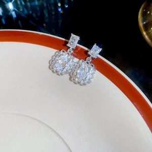 Close-up of elegant silver earrings with zircon stones on a white ceramic tray
