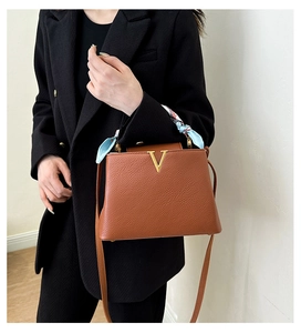 Detailed view of the stylish brown litchi grain handbag with a metallic V logo and silk scarf.