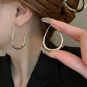 Close-up of minimalist silver teardrop earrings on model for an elegant metal accessory look