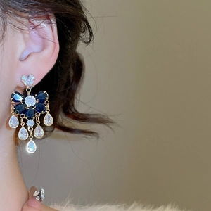 Close-up of gold drop fringe earrings with blue flower gems and clear crystal teardrops