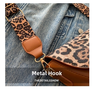 Detailed view of leopard print wide strap and gold metal hook on the saddle bag