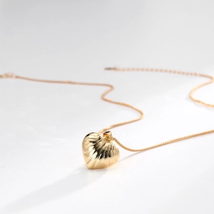 Macro shot of gold-plated hollow heart pendant with artistic leaf-vein textured details