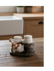 Macro view of a resin chef figure holding two ceramic salt and pepper shakers on wood