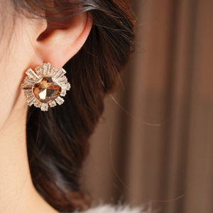 Détail de boucles d'oreilles vintage avec pierre ambre et zircons, portées par un mannequin
