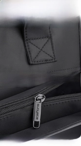 Detail of reinforced X-shaped stitching and branded metal zipper on black nylon bag