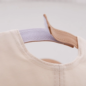 Detail of adjustable velcro strap and premium cotton fabric on beige baby bear cap