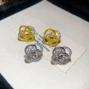 Boucles d'oreilles nœuds or et argent avec zircons sur fond de papier vintage chic