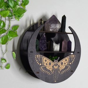 Detail view of black moon-shaped wooden wall shelf with moth engraving and crystals