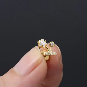 Detalle macro de un pendiente de estrella dorado con micro-engaste de circonita cúbica blanca