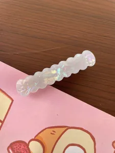 Close-up of wavy iridescent white hair clip with geometric texture and pearlescent finish