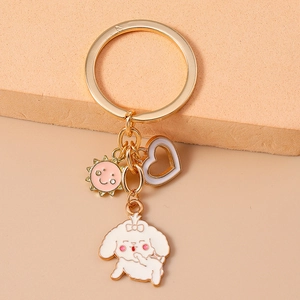 Detailed shot of golden metal keychain with cute white puppy dog and pink sun charms