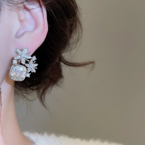 Détails macro de boucles d'oreilles fleurs en zircone sur modèle au fini brillant