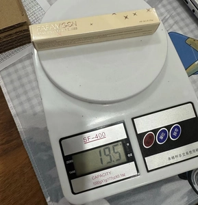 Detalle del empaque del brillo labial FAFAMOON mostrando un peso de 19,5g en la báscula