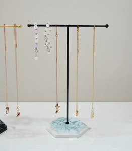 Detail of T-bar jewelry stand with marble base displaying necklaces and bead bracelets