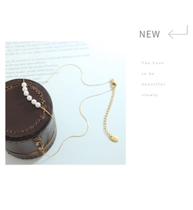 Detailed macro view of five round white pearls on a gold-plated titanium steel necklace