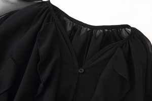 Close-up of V-neckline on black chiffon shirt with ruffled edges and single button detail