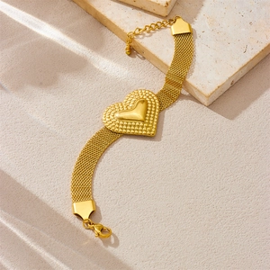 Details eines goldenen Gliederarmbands mit Herzanhänger und Karabinerverschluss aus Edelstahl