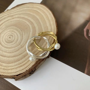 Detail of adjustable pearl rings in gold and silver set on a rustic wood block