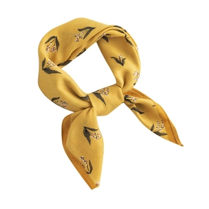 Elegant yellow silk scarf with floral print tied in a knot on a white background