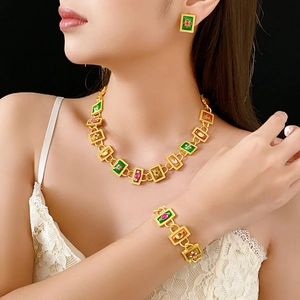 Detail view of vintage gold jewelry set with green and red enamel floral accents