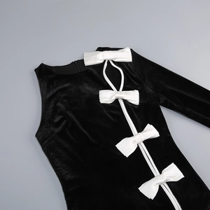 Detail of black velvet dress featuring white satin bow and elegant cutout neckline