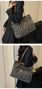 Close-up of leopard print tote bag featuring brown leather handles and metal chain