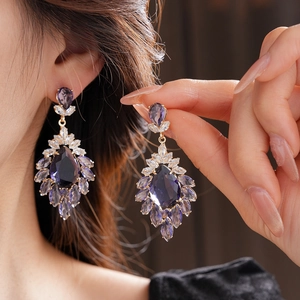 Vue macro de boucles d'oreilles fleurs dorées avec cristaux de zircone violets