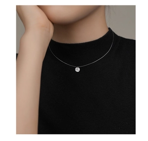 Detail of minimalist invisible fish line necklace with a sparkling round solitaire pendant