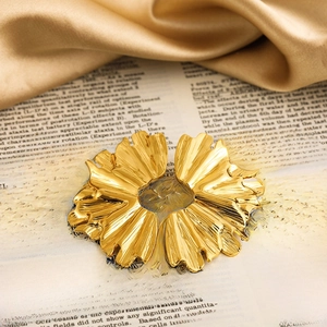 Macro shot of gold-plated petal earrings with textured metal surface on vintage backdrop