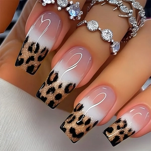 Macro shot of long press-on nails featuring golden leopard print and white heart patterns